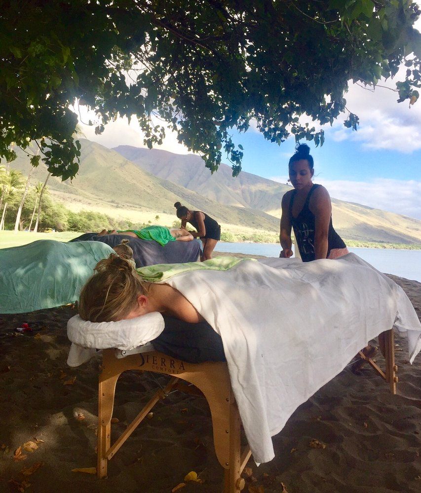 Three people getting massages on the beach.