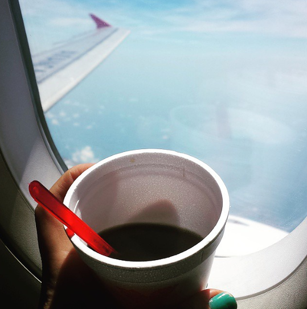 Person drinking coffee on a flight. 