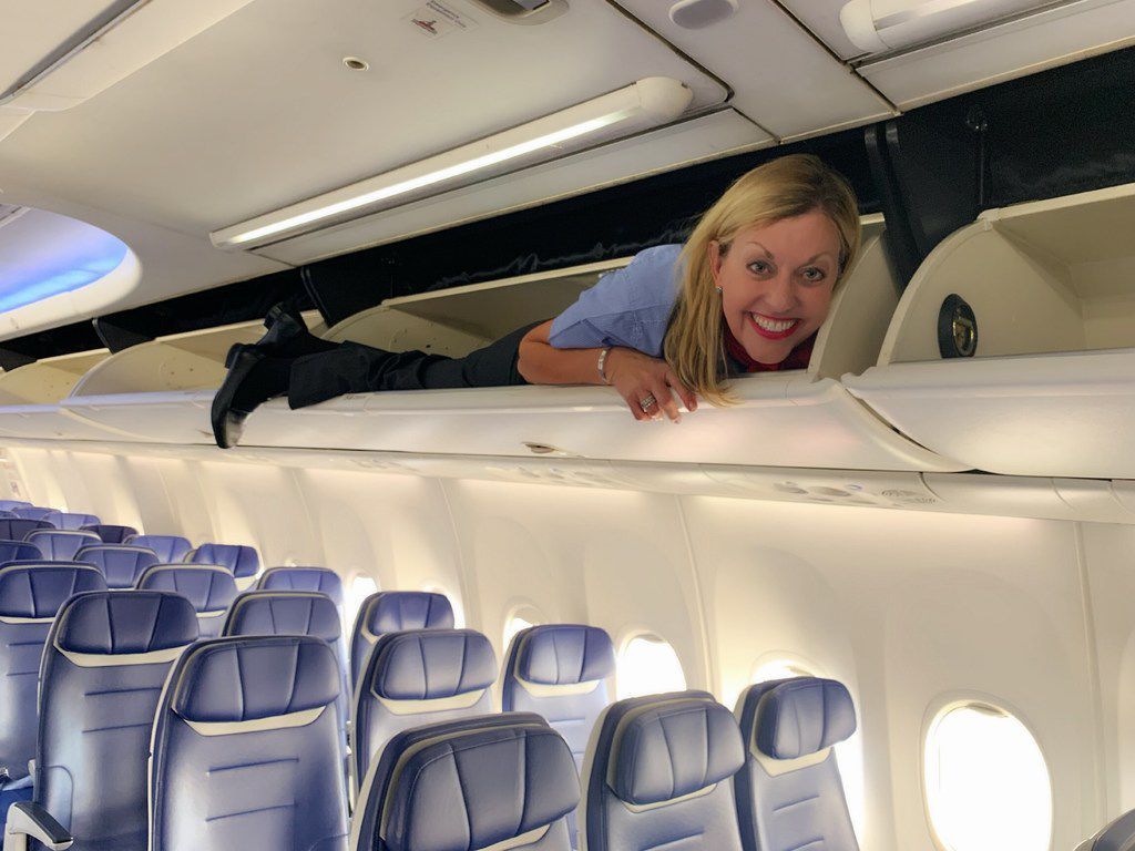 Flight attendant in overhead bin.
