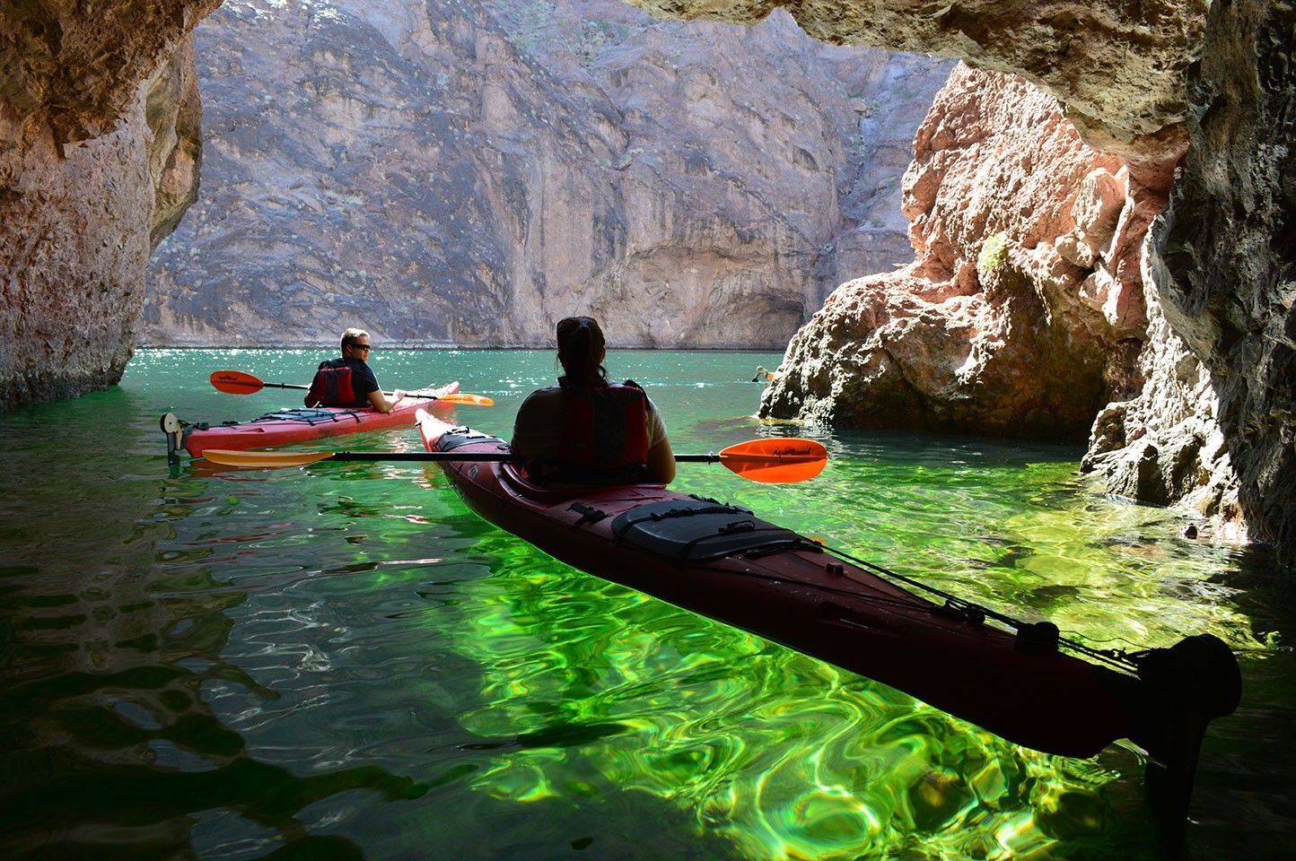 People kayaking under a rock formation