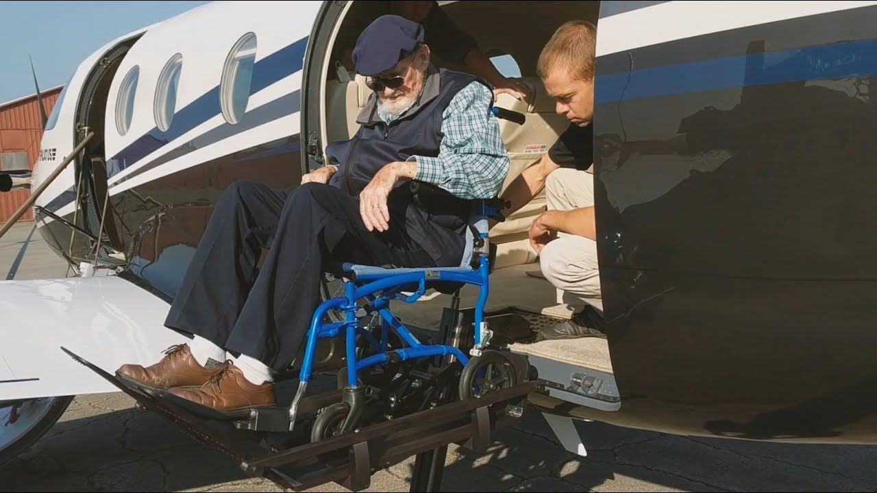 Man getting off of an airplane in a wheelchair