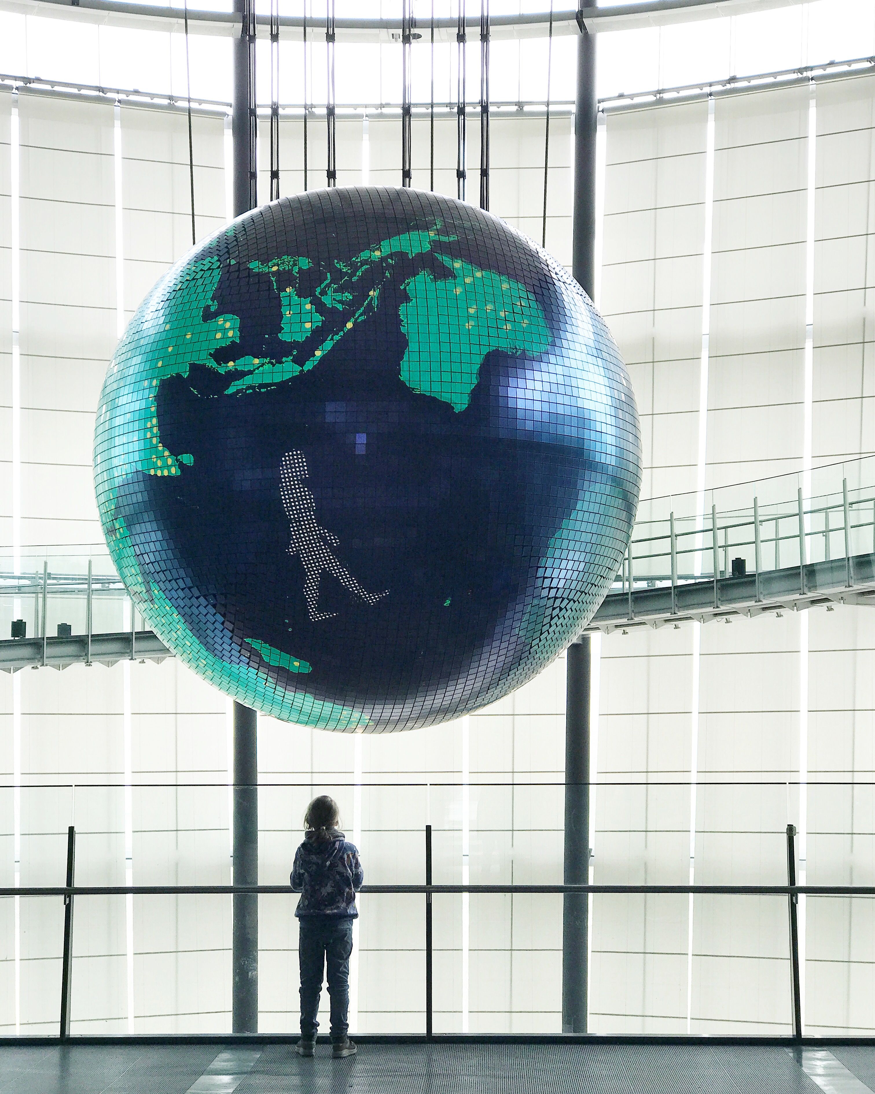 Person standing under a globe installation at the Miraikan Museum in Tokyo Japan