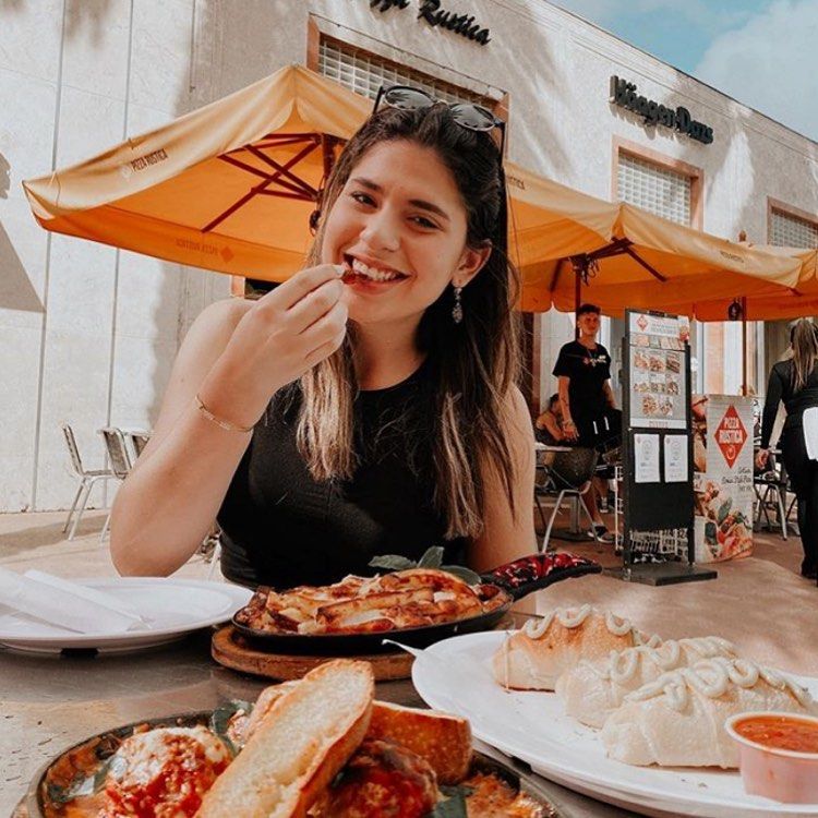 Woman eating outside at Miami's Pizza Rustica 