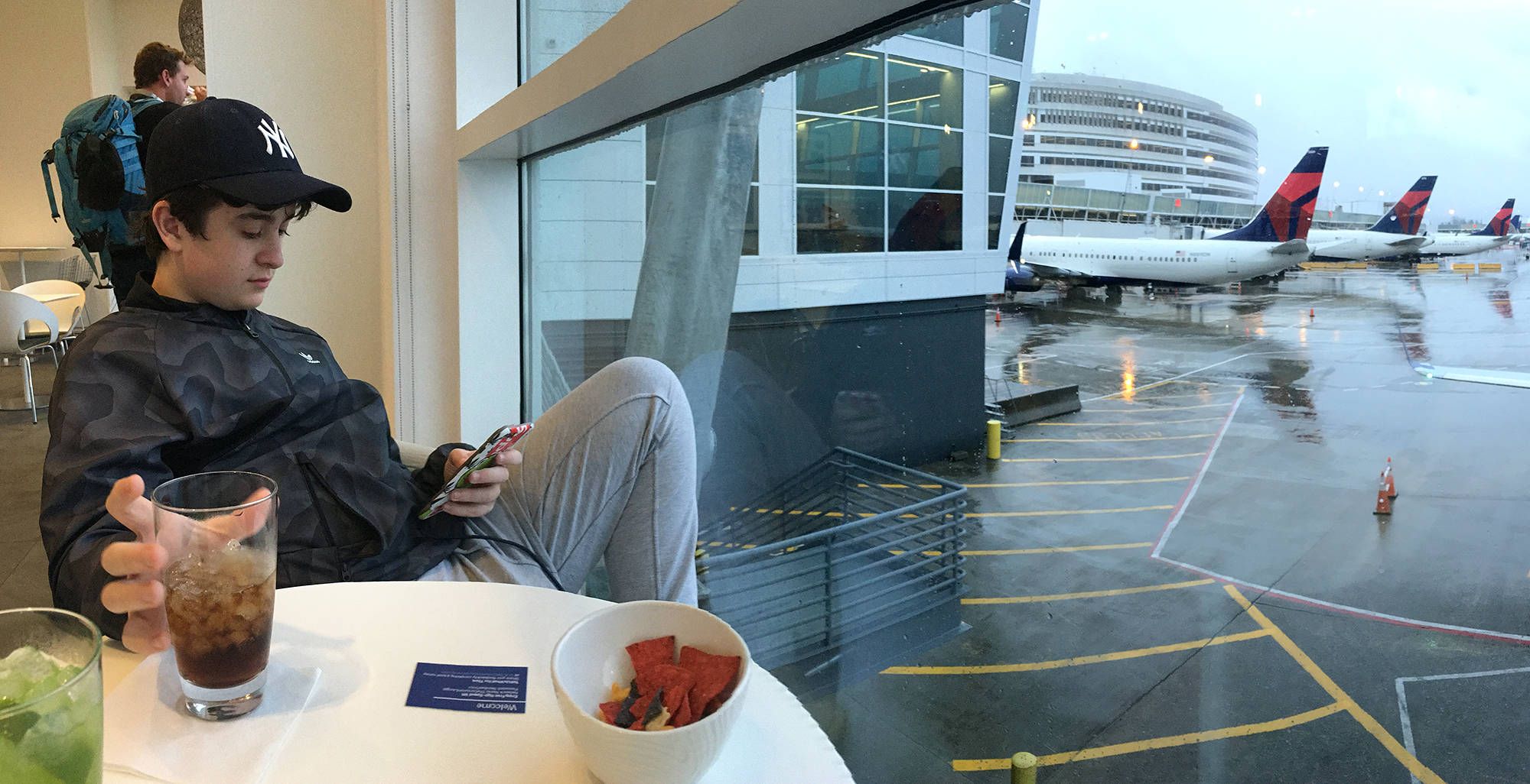 a teen looking at his phone in a private sky lounge 