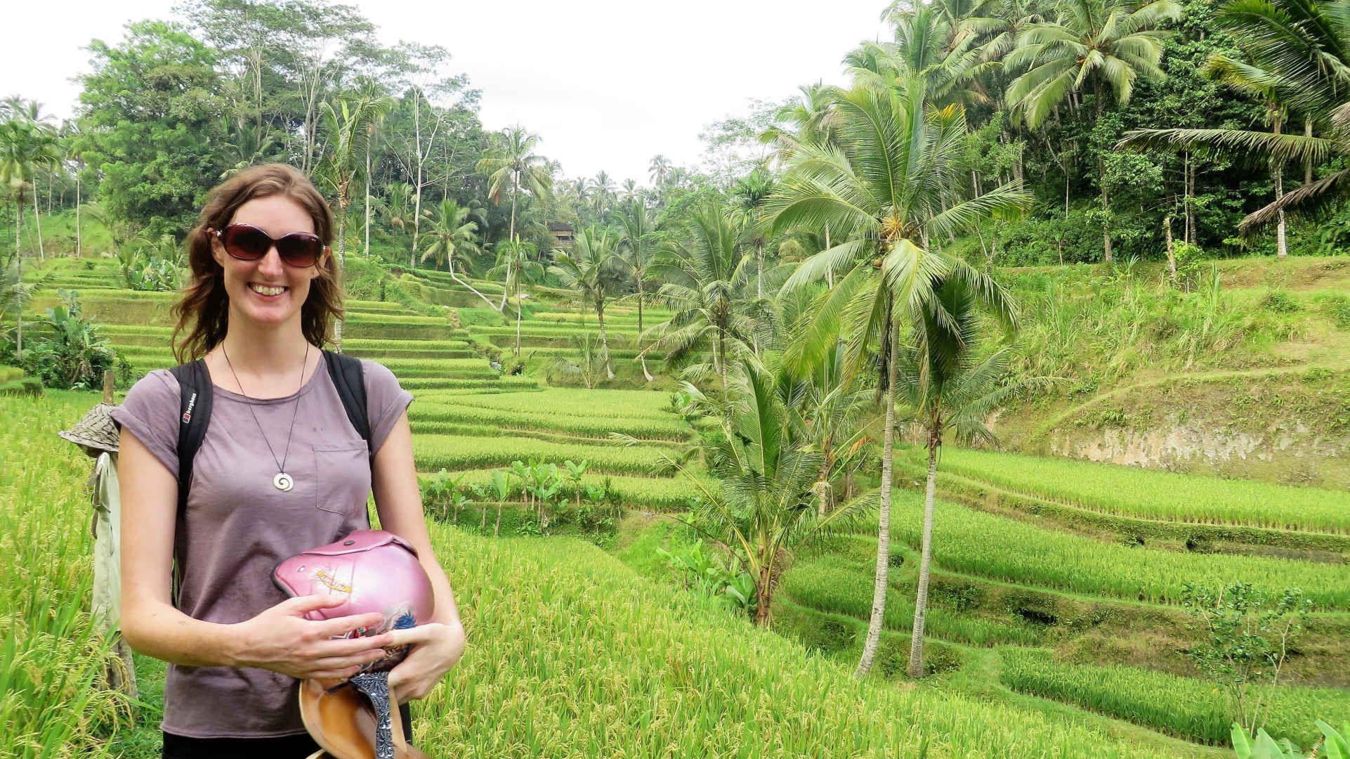 Woman holding helmet in Bali rice terraces
