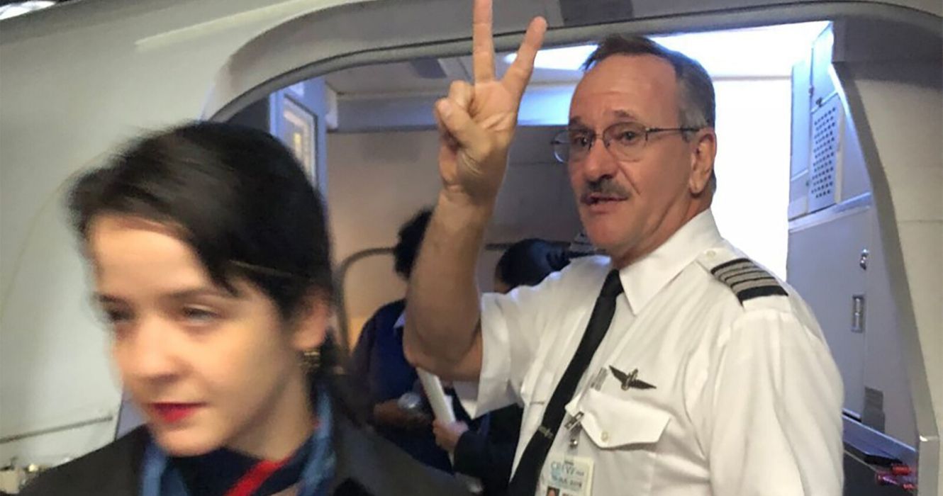 Flight attendant exits airplane, pilot gives the peace sign behind her