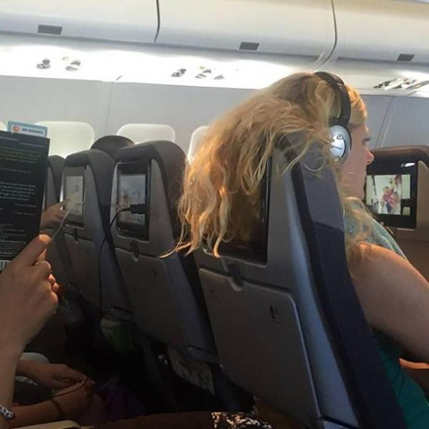 Women covering the airplane tv with her hair