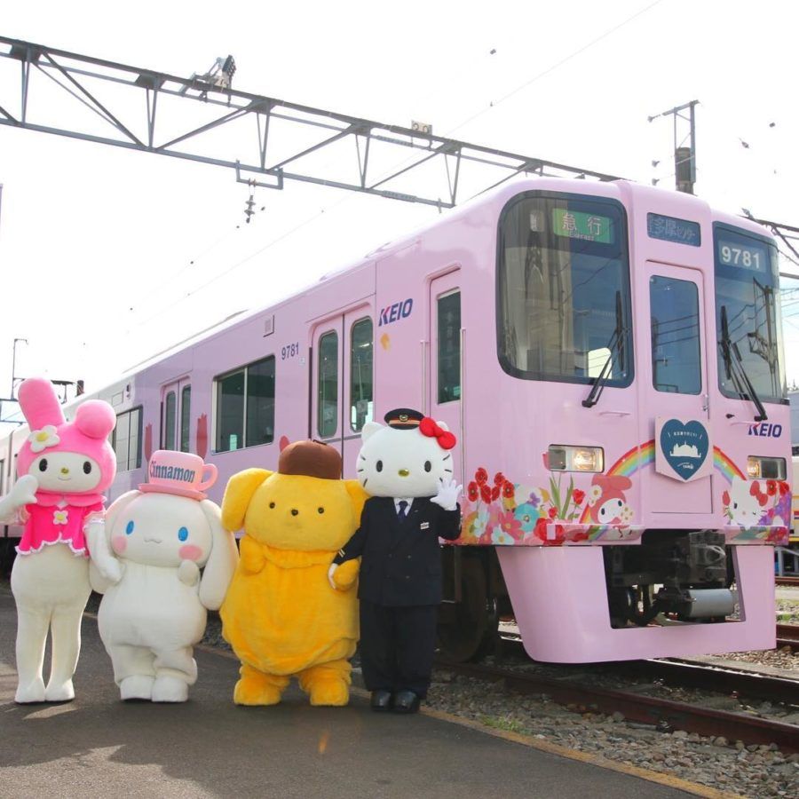 Hello Kitty characters posing by pink Hello Kitty themed train in Tokyo Japan