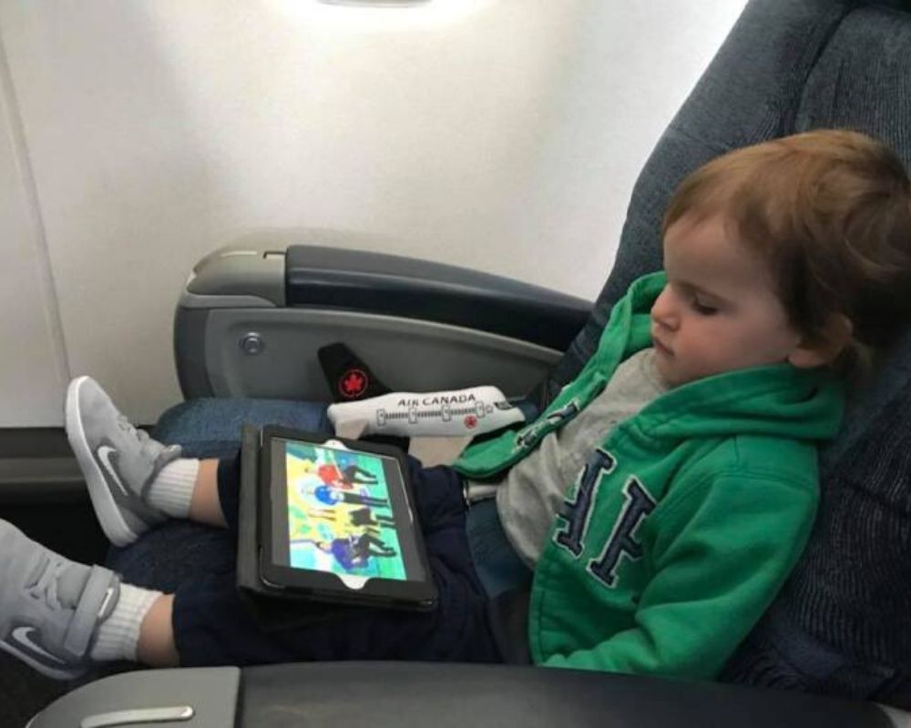 Kid on plane keeping calm, quiet, and watching an ipad
