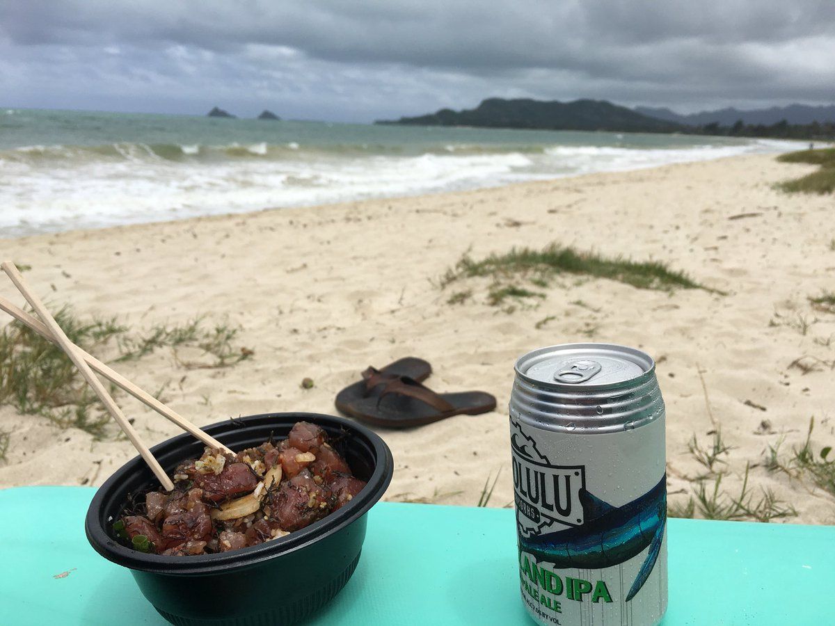 enjoying a fresh poke bowl with a beer on the beach in hawaii