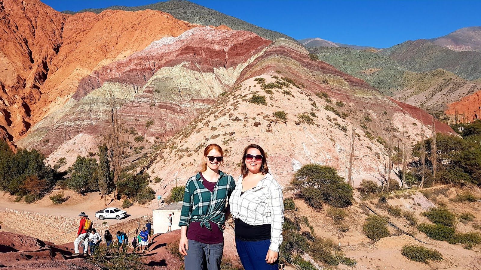 Two women standing in front of rainbow-colored mountain