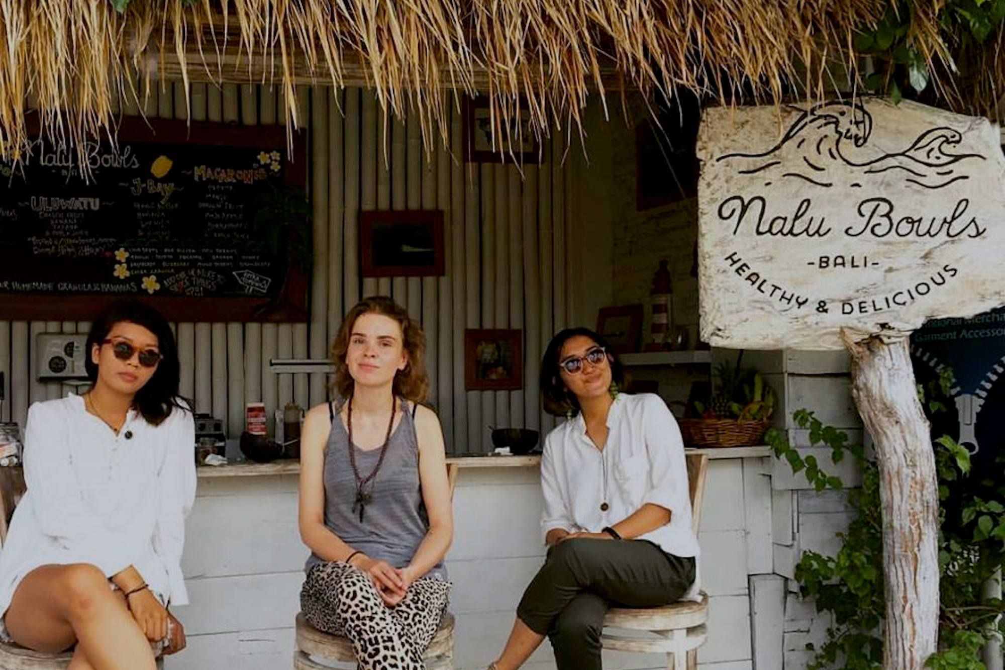 a group of travelers sits outside nalu bowls in bali