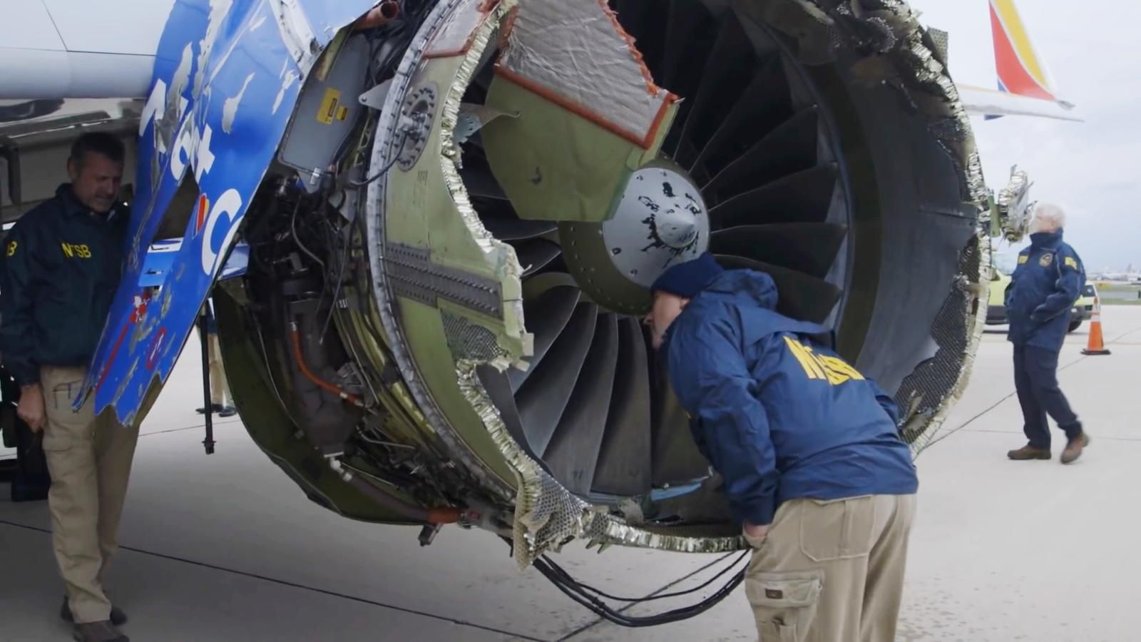 NTSB staff inspect the engine of a Southwest plane on the runway