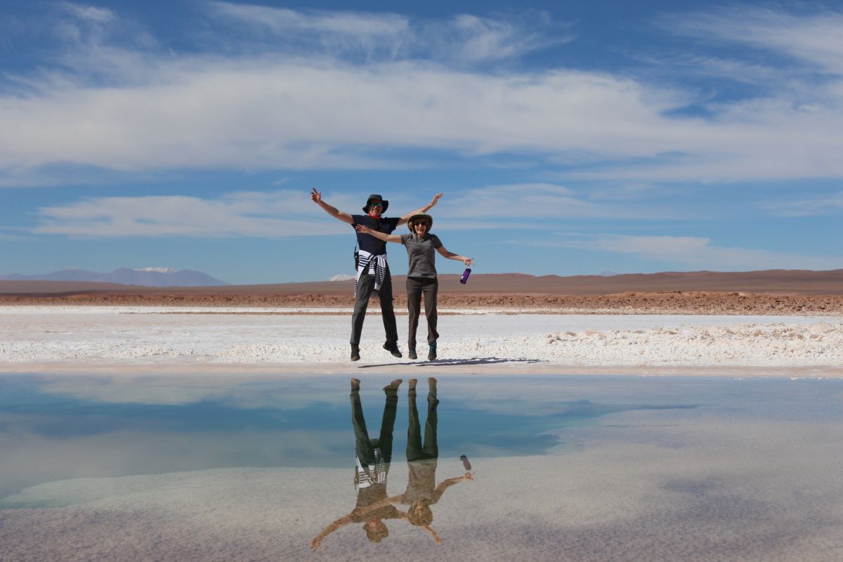 Man and woman standing on wet salt flats