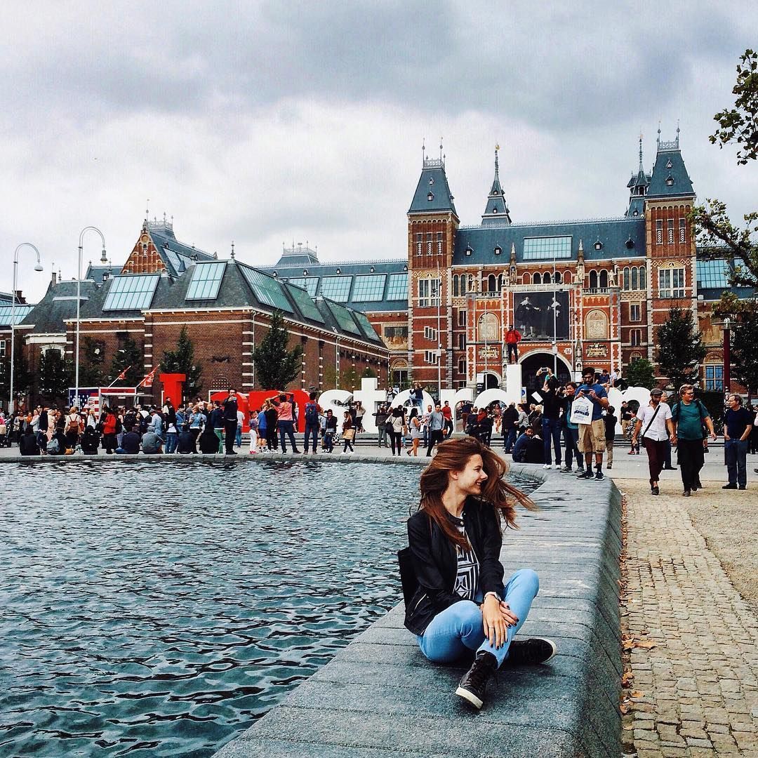 Girl Sitting On Edge Of Water In European City