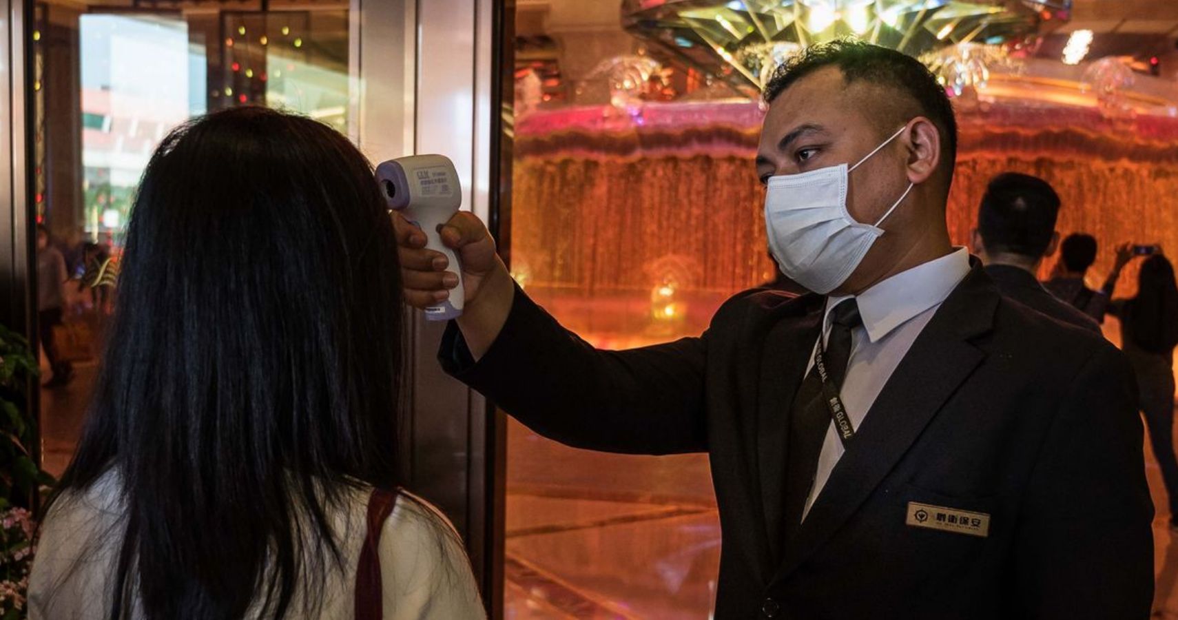 Masked casino attendant checks Macau patron for coronavirus