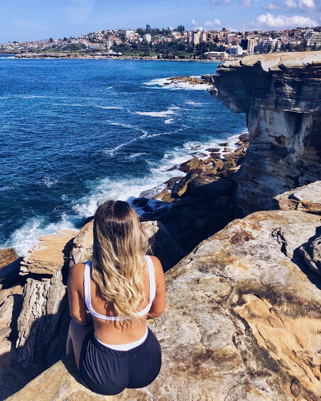 Woman sitting on rocks near beach Australia