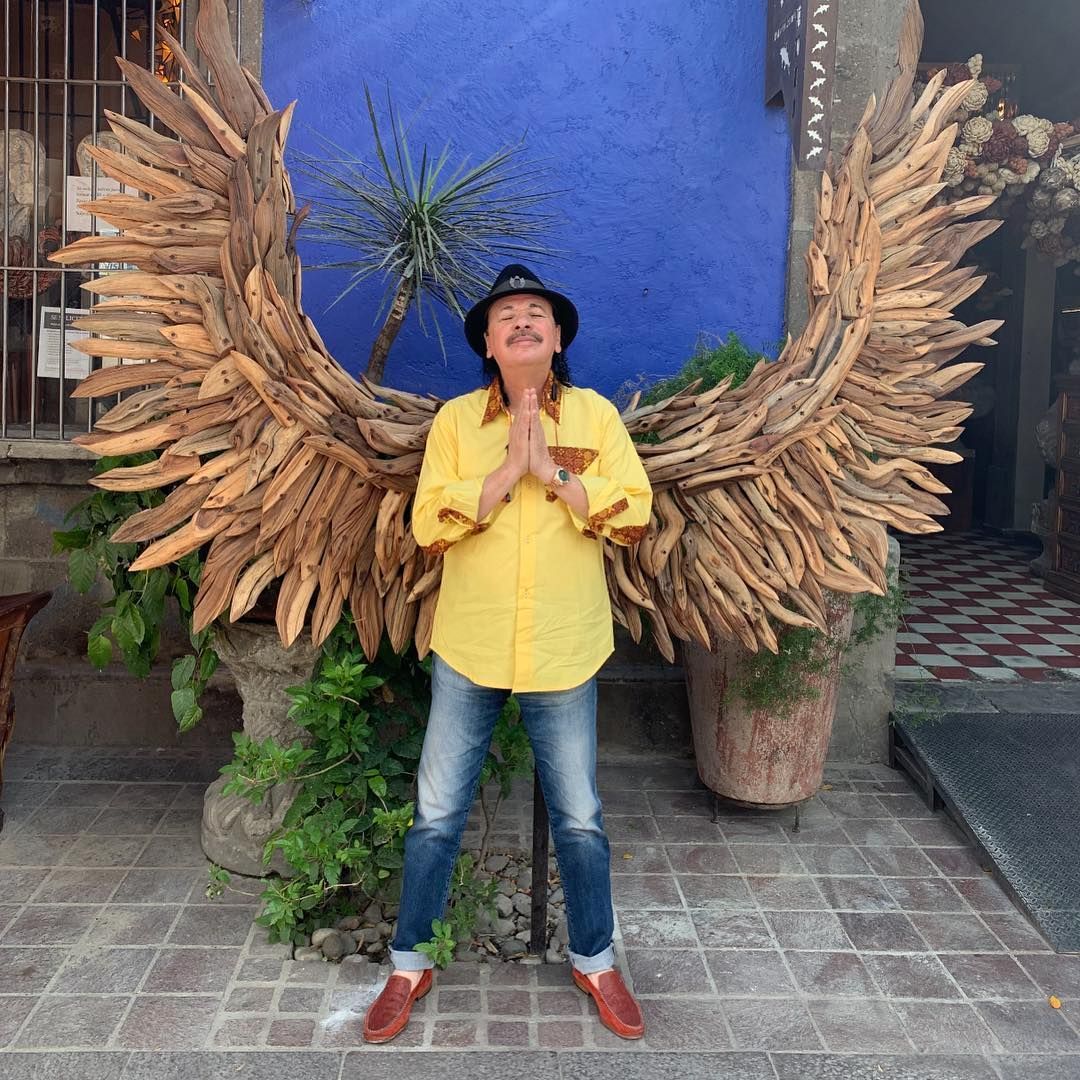 Carlos Santana standing in front of a wing sculpture in Guadalajara MX