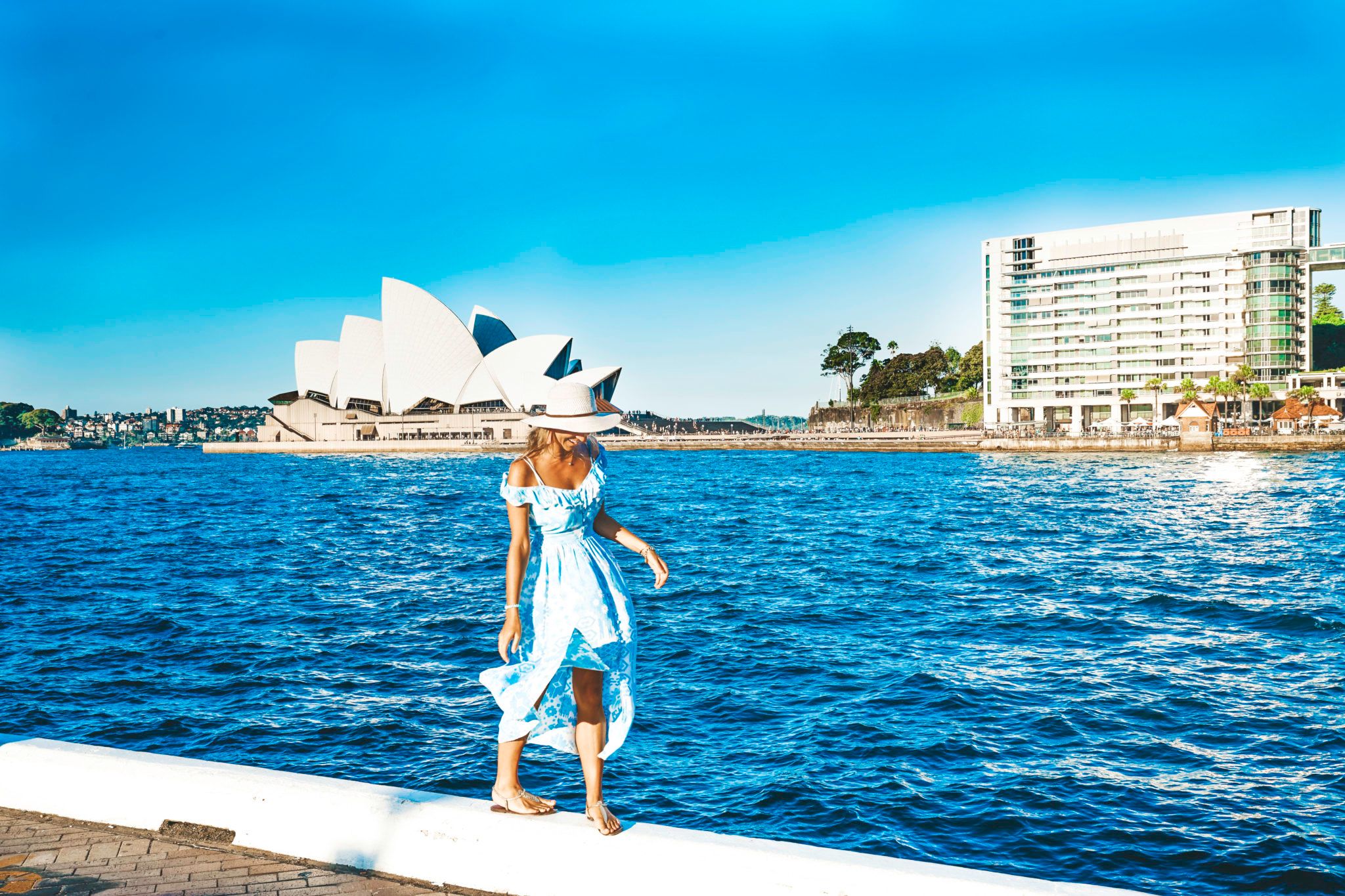 Woman walking along wall with Sydney Harbour and the Opera House in the background
