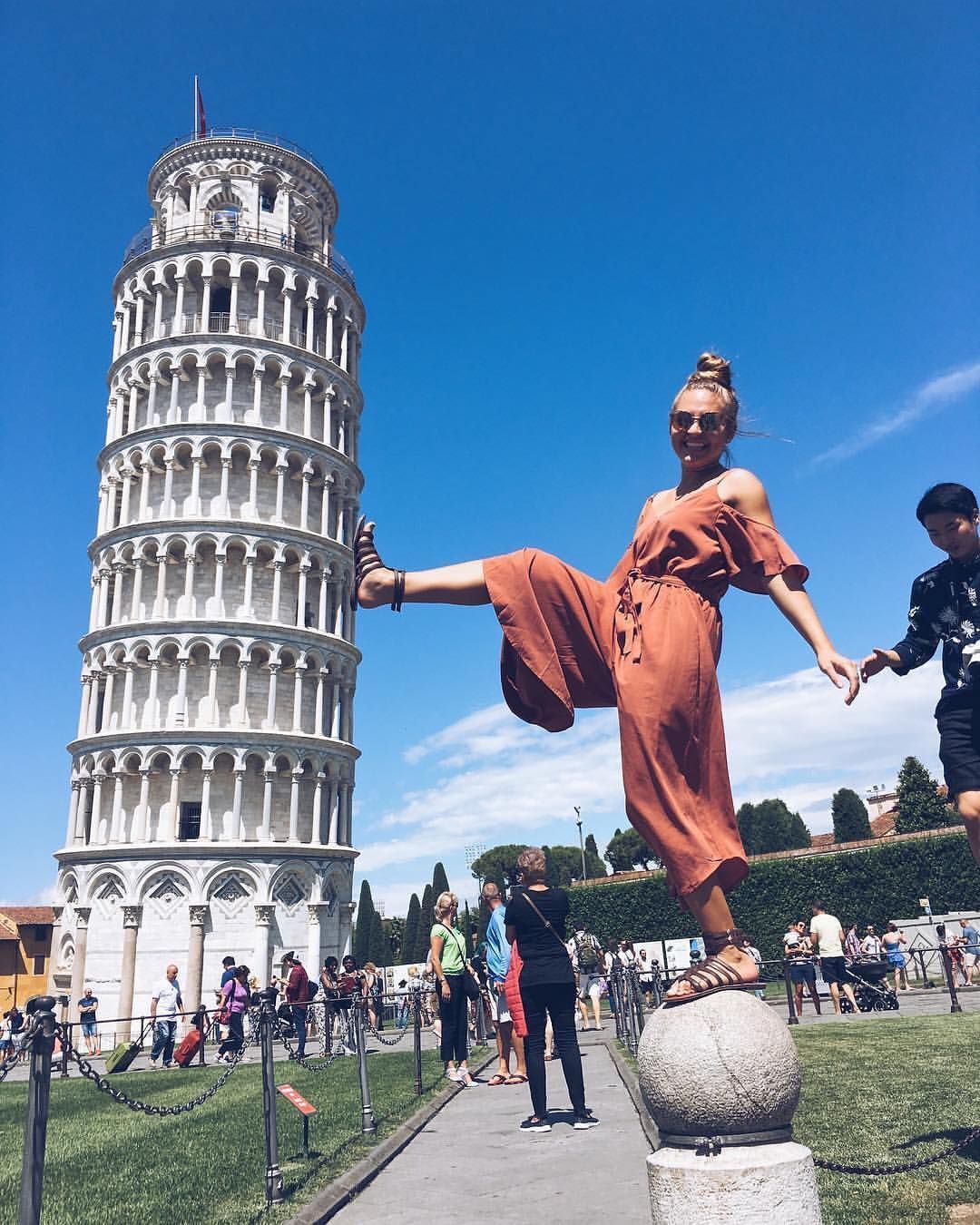 Woman posing by the Tower of Pisa in Italy with her foot up