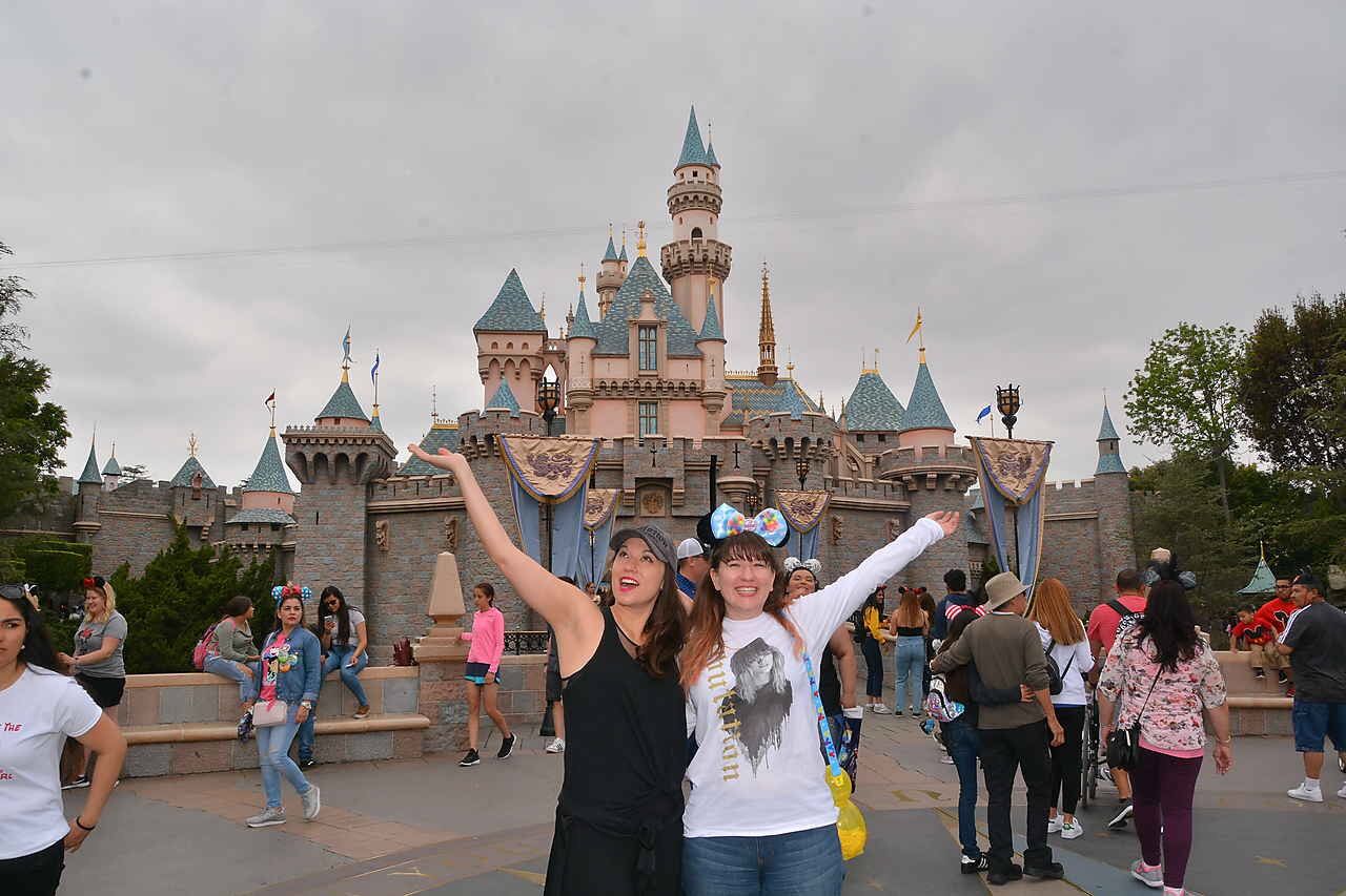 two women standing in front of the Disney castle