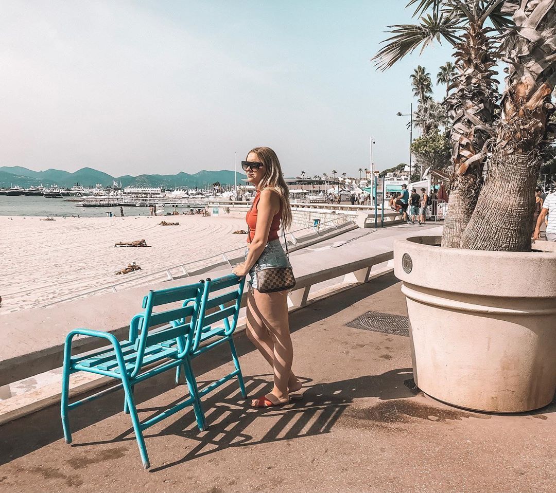 Woman standing behind a bench looking at La Croisette Beach in Cannes France