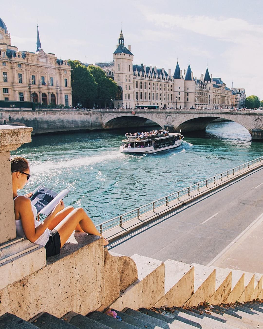 Woman reading while sitting along the bank of the Seine River in France