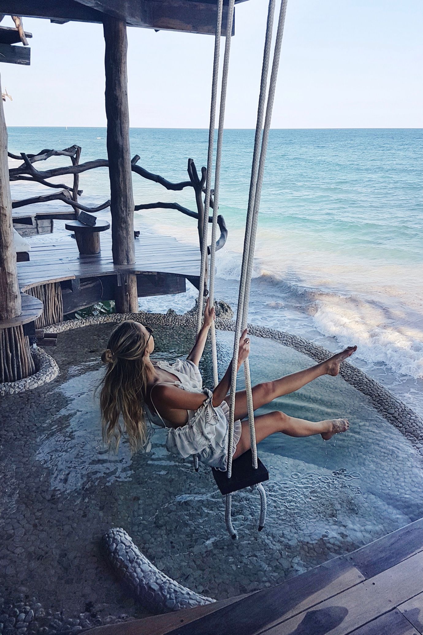 a woman swings overlooking the ocean in a makeshift swing in mexico