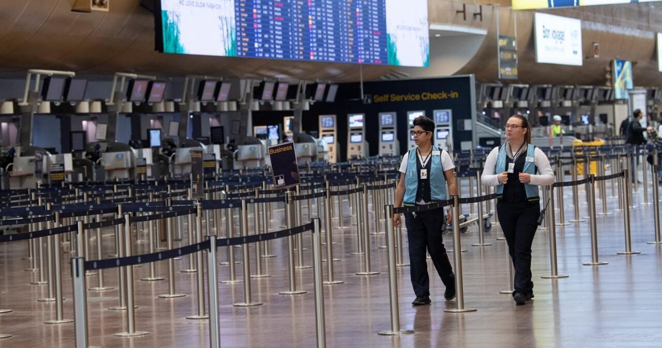 airport staff walk past an empty line for airline checkin
