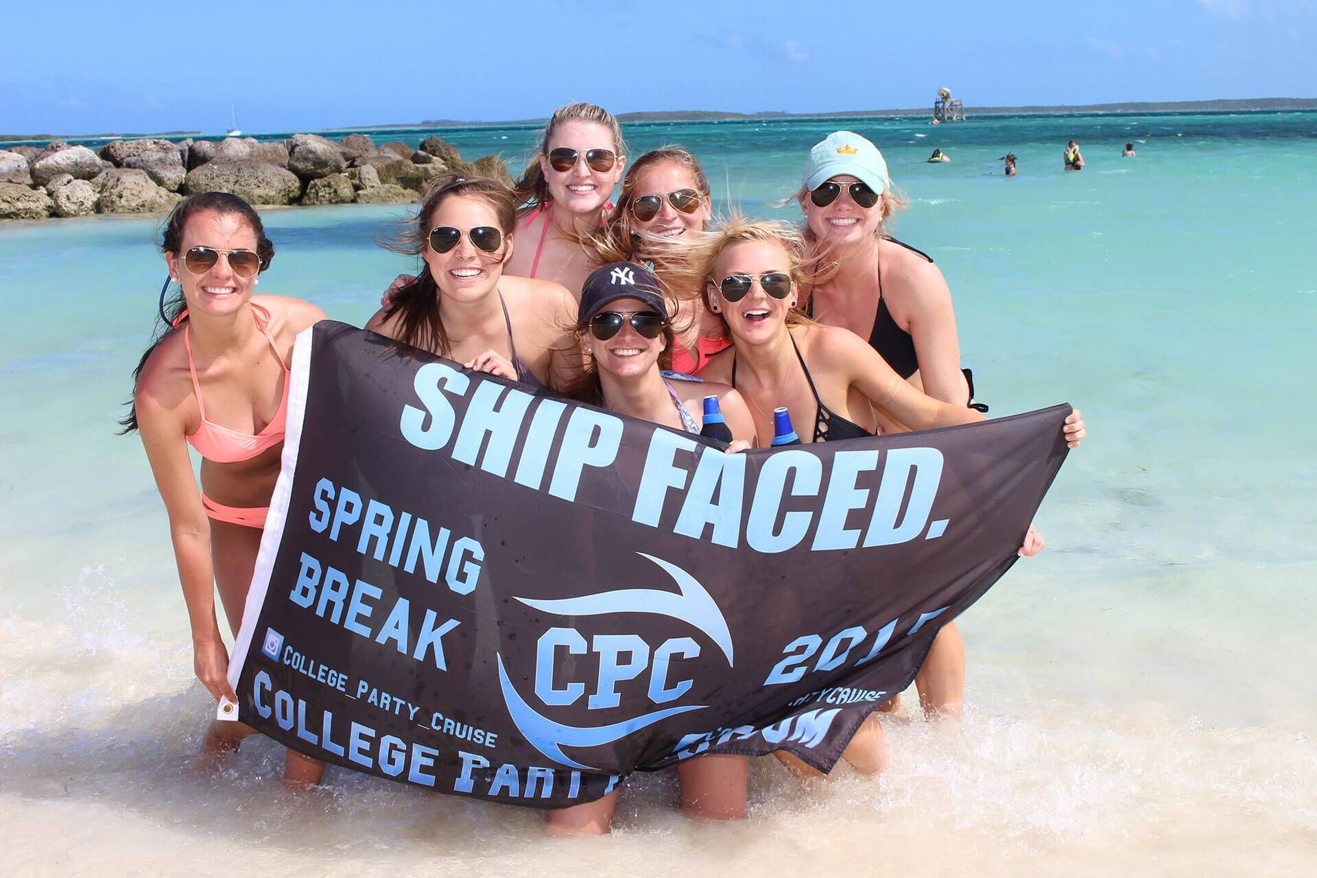 Group of college students on a beach holding a sign that says Ship Faced