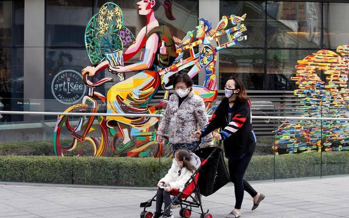 a family wearing a protective mask takes a walk outside 