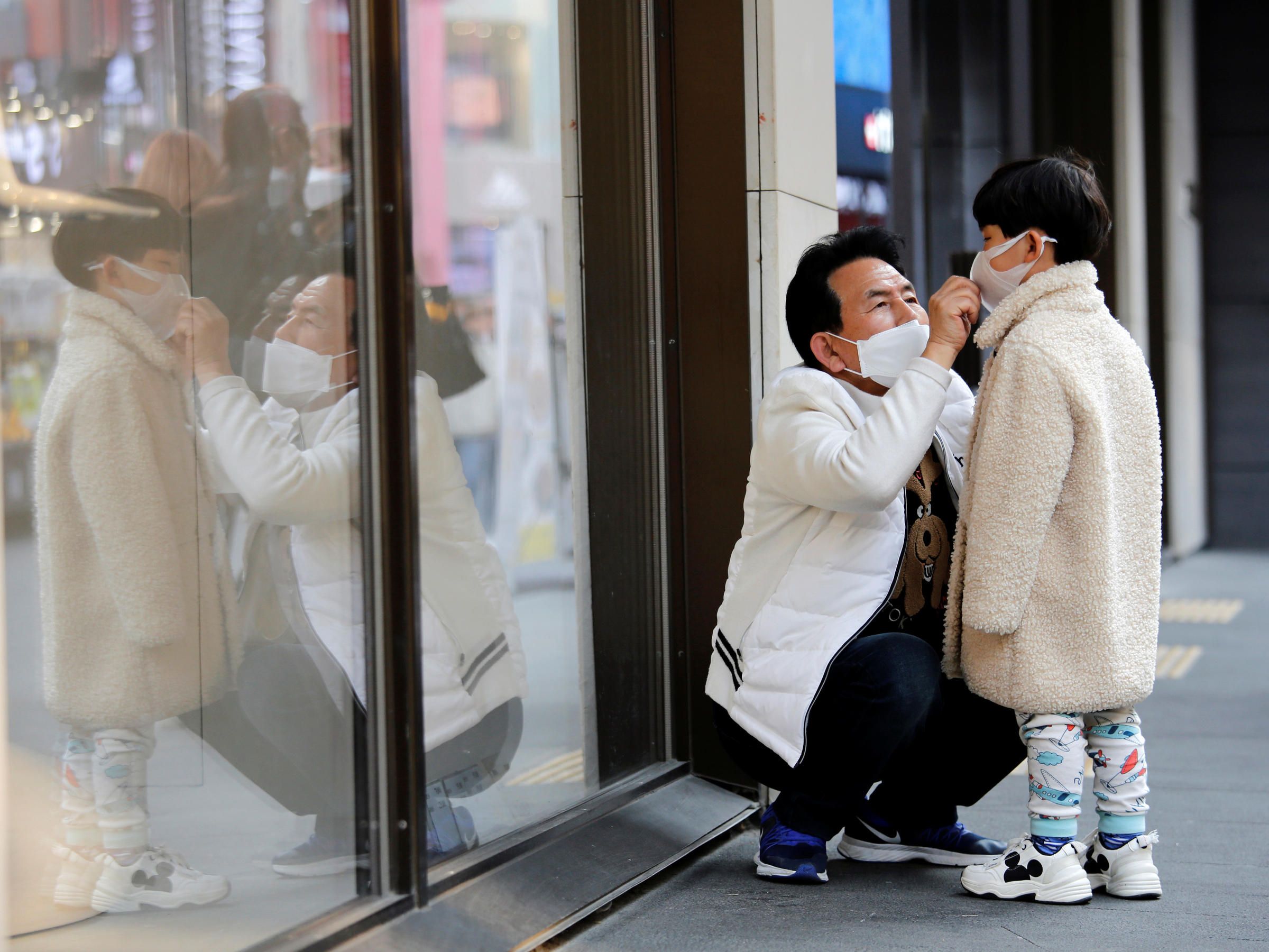 a father adjusts a child's protective mask