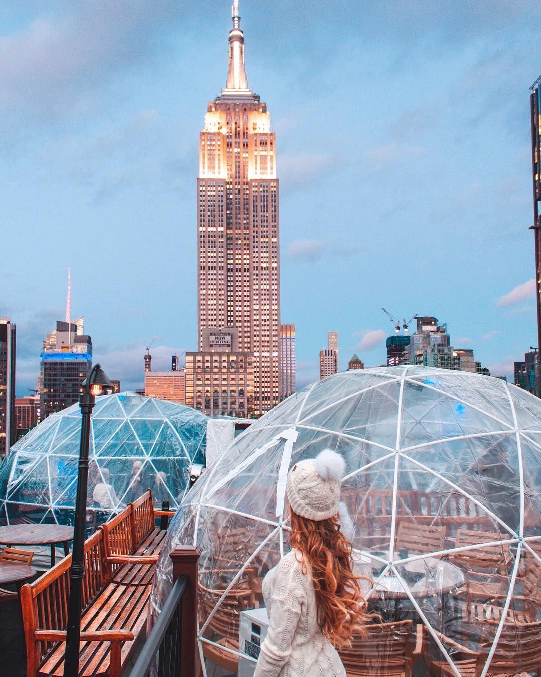 woman stands inside igloo overlooking empire state building