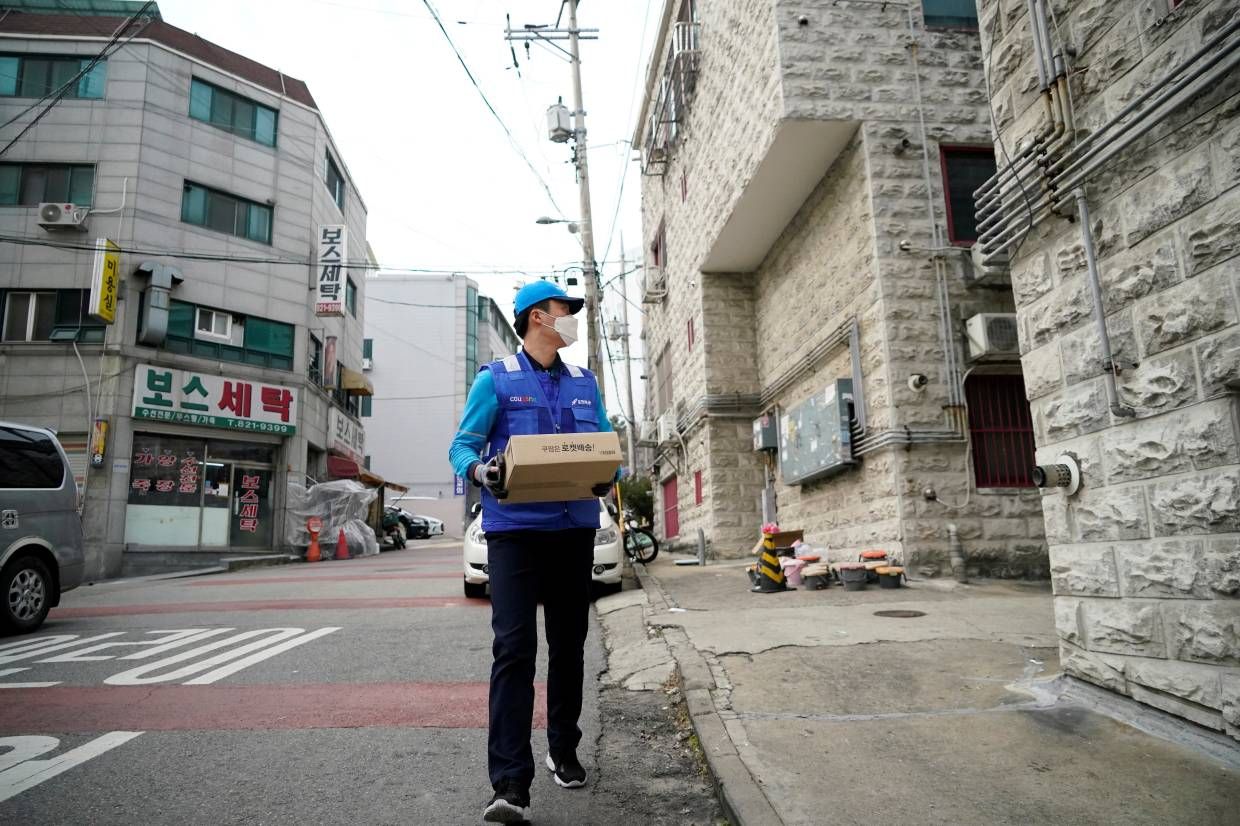 a parcel delivery man in blue wearing a protective mask delivers a box