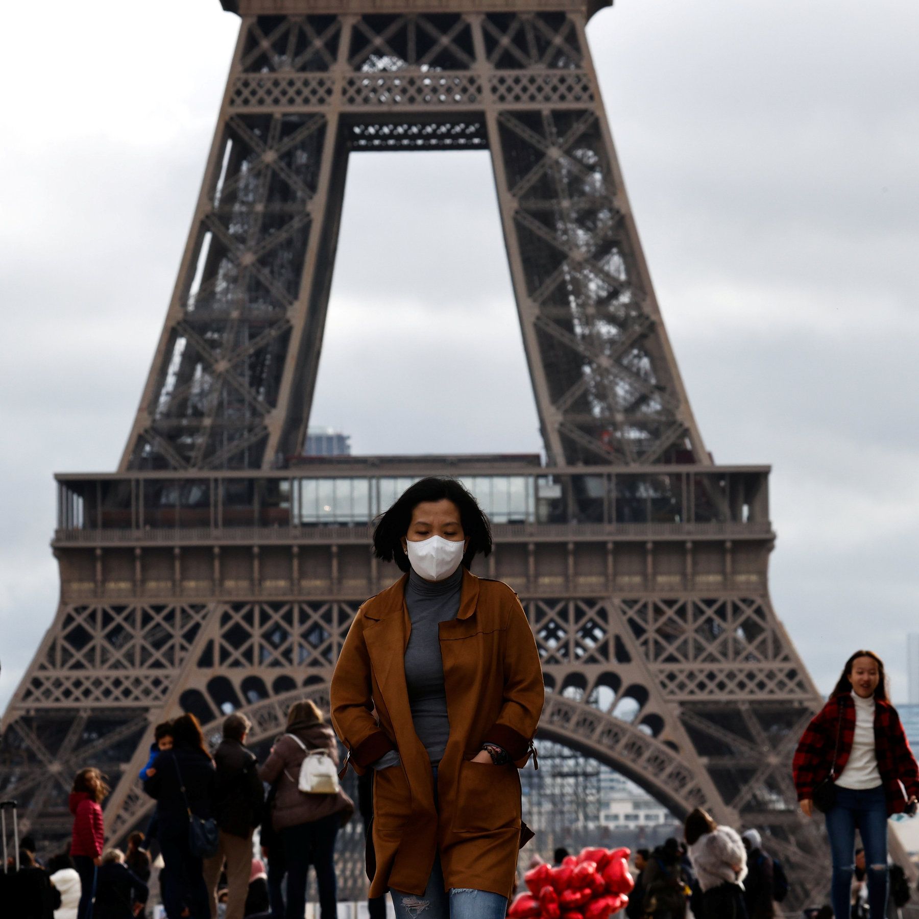 A woman wearing a mask in front of the Eifell Tower.