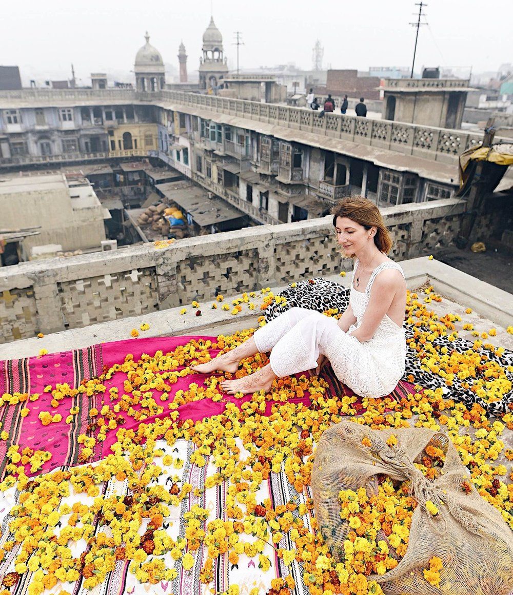 Woman sitting on a rooftop in New Delhi with flowers all around her