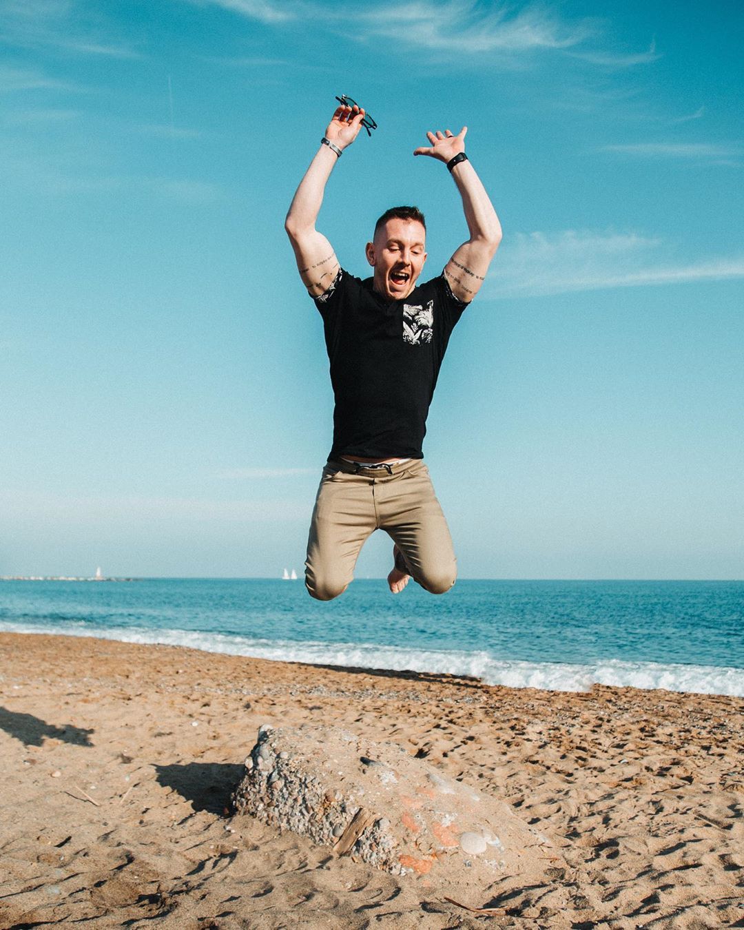 Guy jumping at Barceloneta Beach in Spain