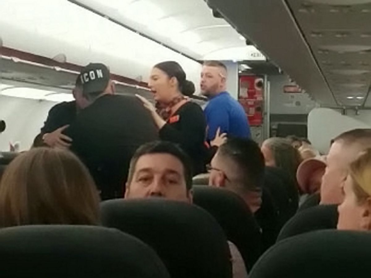 Flight attendant calming people down on an airplane