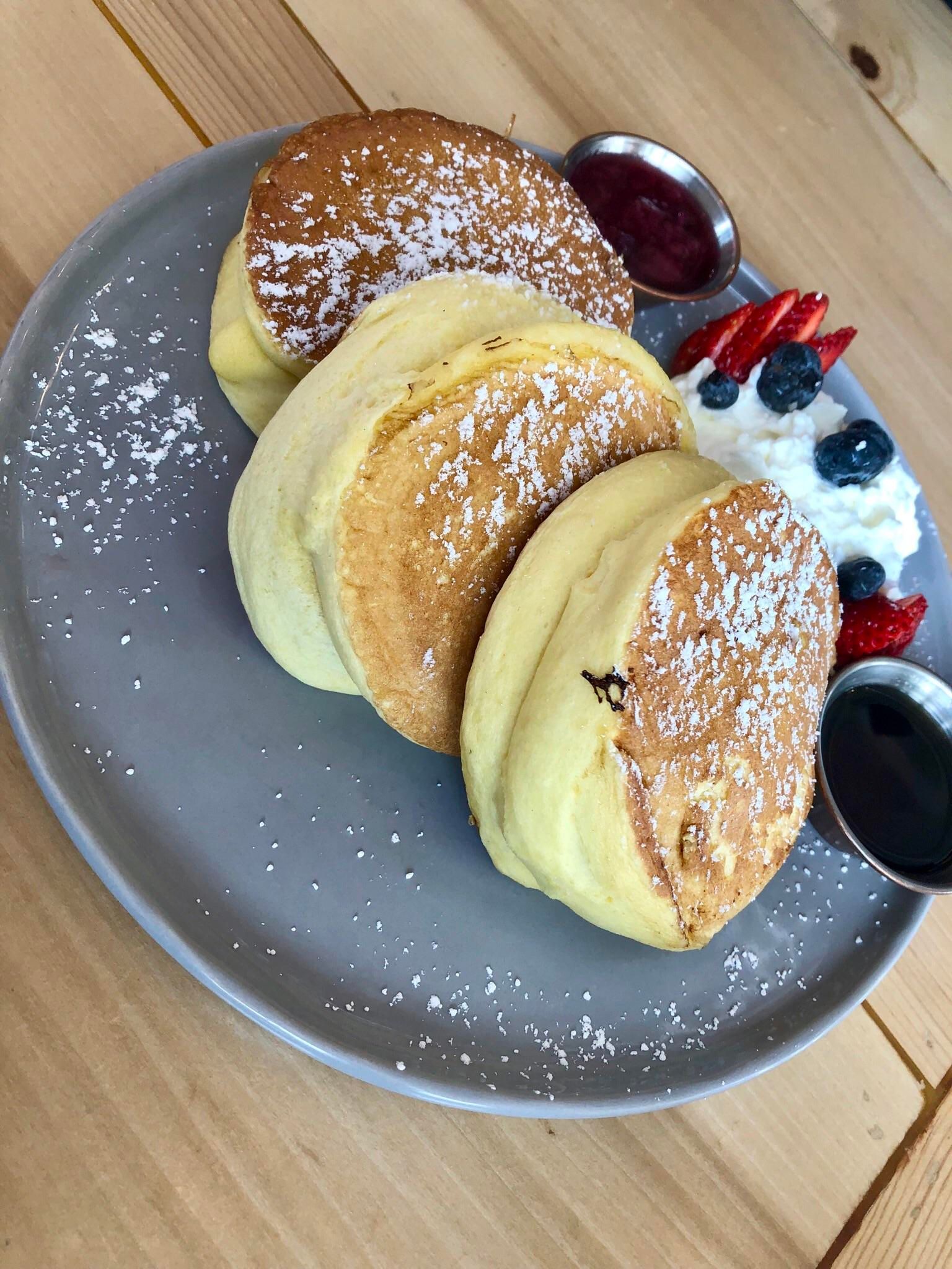 fluffy pancakes in japan on blue plate with berries on side
