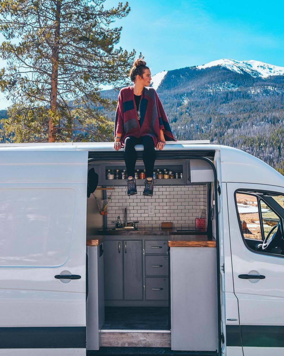 a girl sits on top of a motorhome