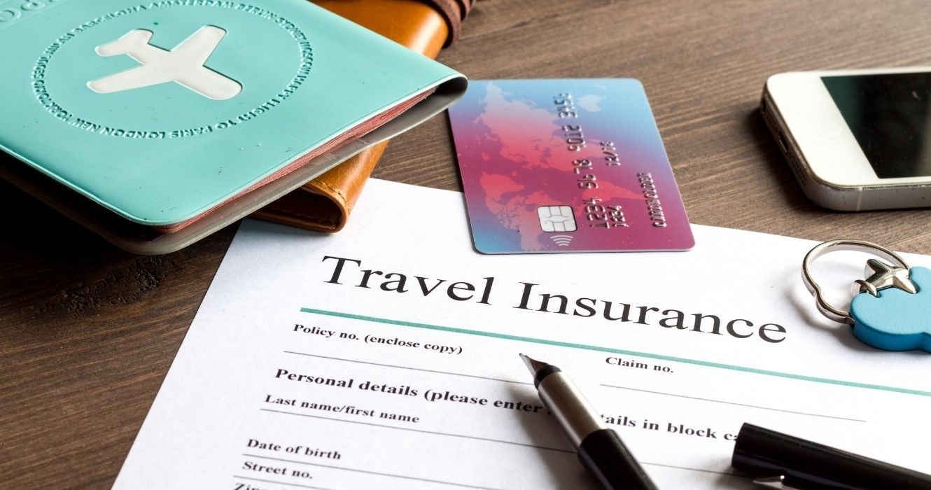A travel insurance policy with a passport and other items on the table 