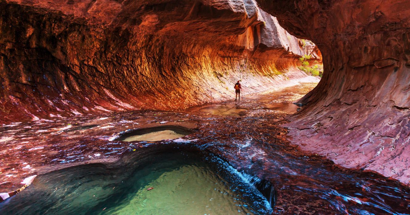 A hiker hiking along The Subway, Zion National Park, Utah 