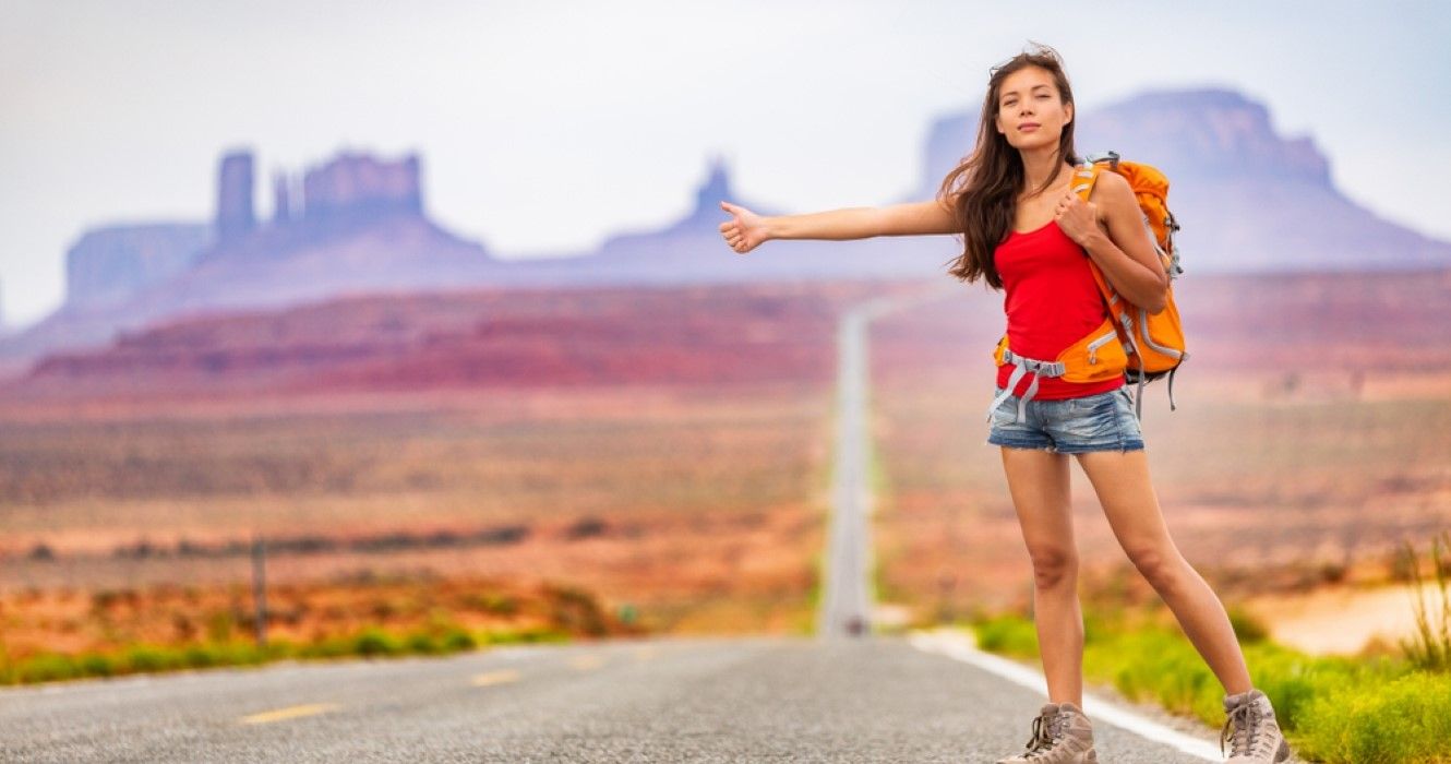 Woman backpacking and hitchhiking on road trip
