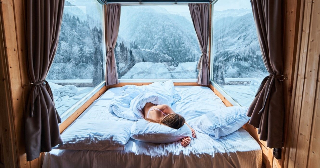 Woman sleeping in a resort with snowy mountain views