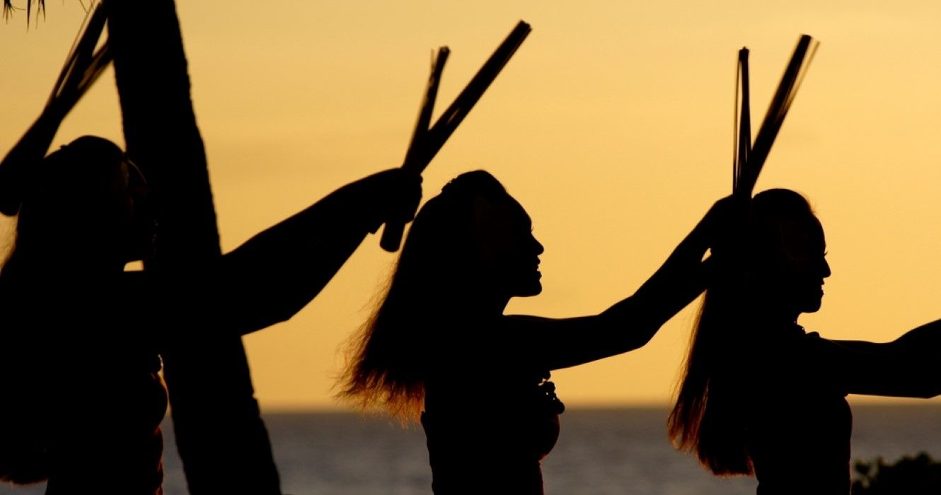 Luau dancers against a sunset sky on Oahu
