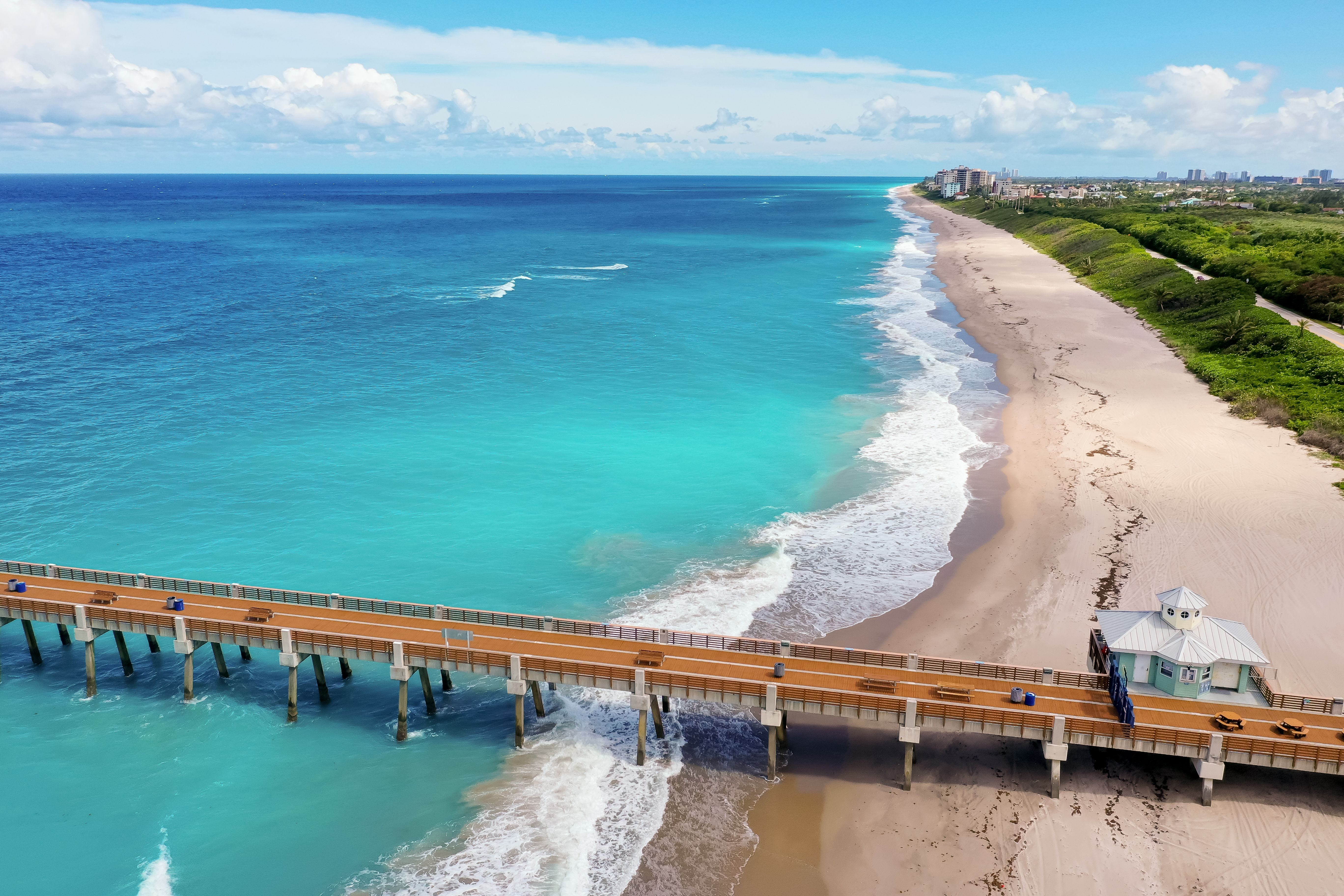 Pier and lifeguard stand over the golden sands and turquoise waters of Juno Beach, Florida, USA