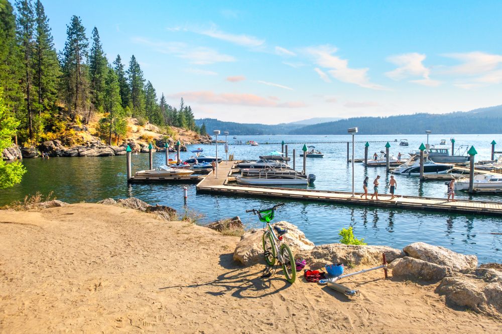 A child's scooter and bicycle sit on the shores of Lake Coeur d'Alene near the resort marina