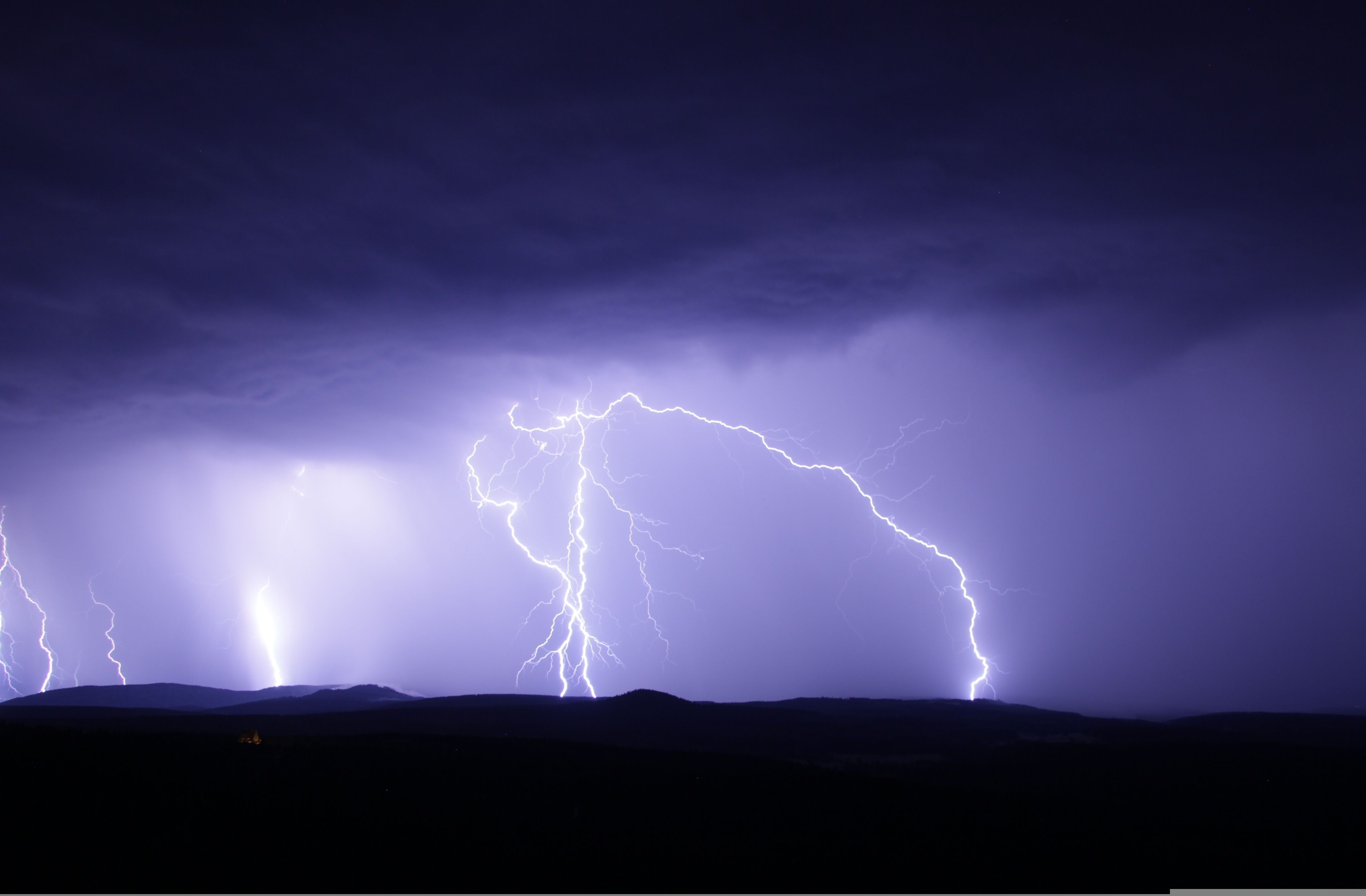 A thunderstorm at night with lightening strikes illuminating the sky