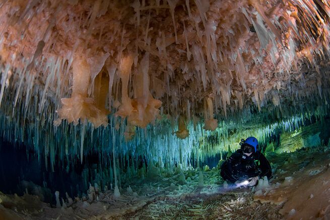 Diver looking at large rose colored crystals in the glass factory of the Bahamas' crystal cave