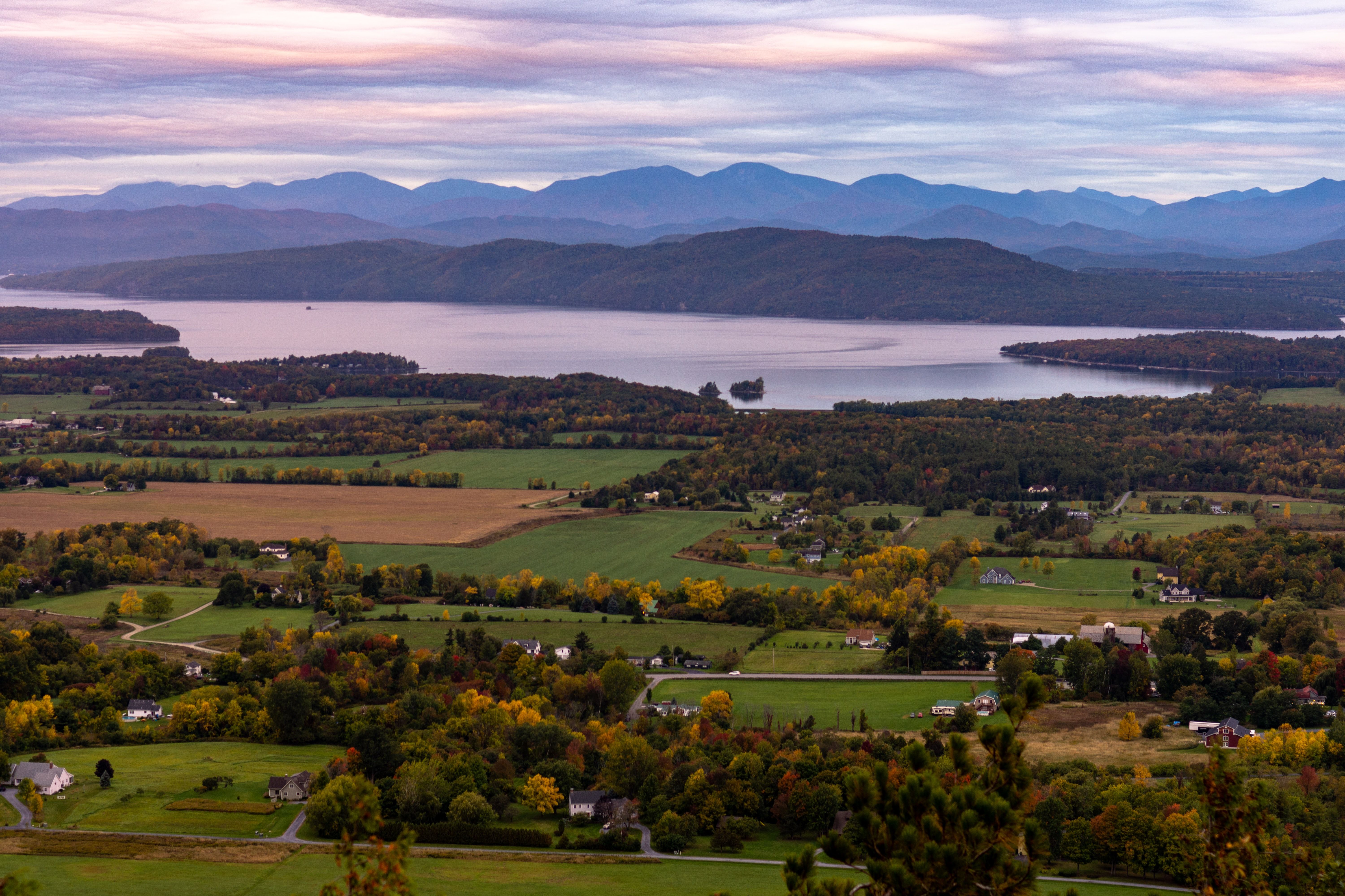 Aerial picture of Champlain Valley in Vermont with houses, a lake, and mountains in the background